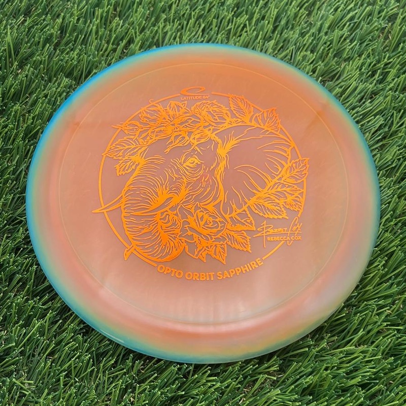 Latitude 64 Opto Ice Orbit Sapphire with Rebecca Cox Team Series 2025 Stamp – 162.51g – Teal Orange